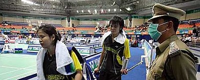 Masked protector: Malaysia&rsquo;s Sabrina Chong and Ong Jien Guo walking past a masked security personnel after losing to Chinese mixed doubles pair He Hanbin-Yu Yang yesterday.