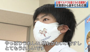 Student wearing facemask that has faces of Kento Momota, Yuta Watanabe, and Arisa Higashino. (photo: Fukushima TV)