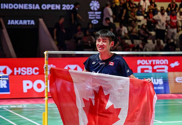 Victor Lai celebrates with a Canadian flag after defeating Jonatan Christie to win the Indonesia Open badminton men’s singles title in Jakarta. (Photo: AFP)